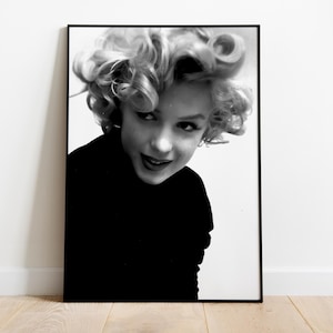 Peut inclure: Photographie en noir et blanc d'une femme aux cheveux boucl&eacute;s. Elle porte un pull noir &agrave; col roul&eacute; et regarde l'appareil photo.