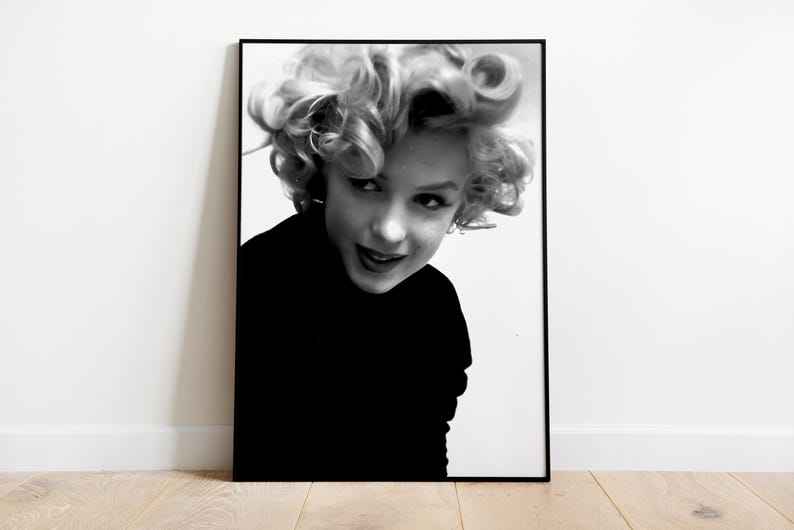 Peut inclure: Photographie en noir et blanc d'une femme aux cheveux boucl&eacute;s. Elle porte un pull noir &agrave; col roul&eacute; et regarde l'appareil photo.