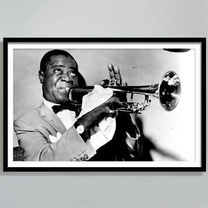 May include: A black and white photograph of a man playing a trumpet. He is wearing a suit and a bow tie. The trumpet is held in his right hand and he is looking at the camera.