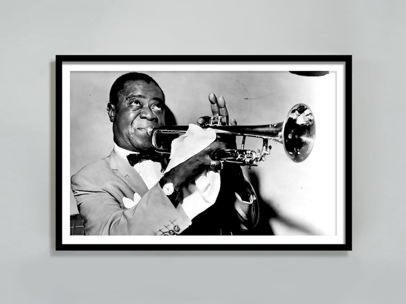 May include: A black and white photograph of a man playing a trumpet. He is wearing a suit and a bow tie. The trumpet is held in his right hand and he is looking at the camera.