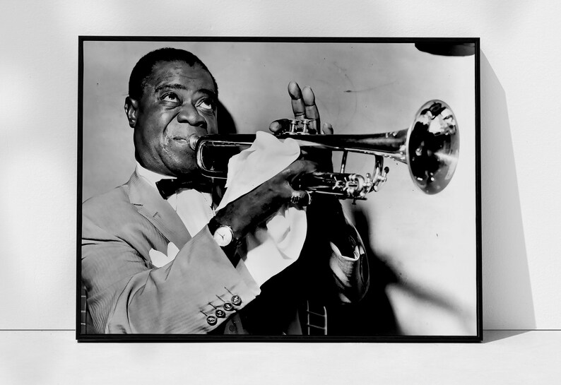 May include: A black and white photograph of a man playing a trumpet. He is wearing a suit and a bow tie. The trumpet is held in his right hand and the bell of the trumpet is pointed towards the right side of the image.
