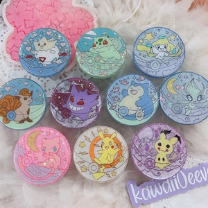 May include: Ten colourful round phone grips featuring different Pokemon characters. Each grip has a sparkly, iridescent finish and features a different Pokemon character, including Pikachu, Squirtle, Bulbasaur, Charmander, and more.