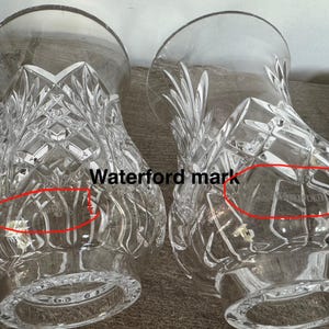 May include: Two clear crystal vases with diamond-cut patterns. The vases have a wide base and a flared top. The word "Waterford" is etched on the side of each vase. These decorative vases are ideal for displaying flowers.