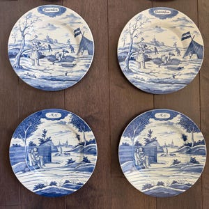 May include: Four blue and white decorative plates with pastoral scenes. Two plates are labeled "December" and depict winter activities. The other two plates are labeled "May" and show figures in a landscape. The plates have a classic, vintage aesthetic.
