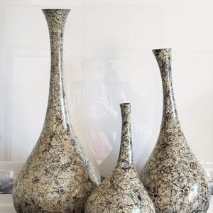 May include: Three ceramic vases in different sizes with a white and black marbled pattern. The vases are tall and slender with a rounded bottom.