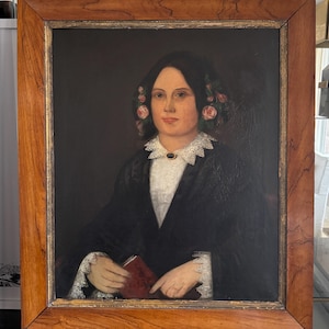 May include: A framed oil painting of a woman in a black dress with a white lace collar. She is wearing a crown of pink roses in her hair and holding a red book. The painting has a dark background.