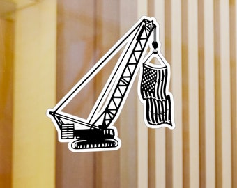 May include: A black and white illustration of a crane lifting an American flag. The crane is a construction vehicle with a long arm and a hook. The flag is hanging from the hook and is waving in the wind.