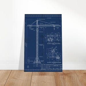 May include: A blueprint-style architectural print of a tower crane, rendered in white lines on a deep blue background. The detailed diagram includes various sections and measurements, showcasing the crane's structure and components. The print is displayed against a white wall and wooden floor.
