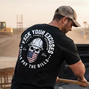 May include: Black t-shirt with a graphic on the back featuring a skull wearing a hard hat and an American flag bandana. The text around the skull reads "F*ck Your Excuses" and "Skills Pay The Bills."