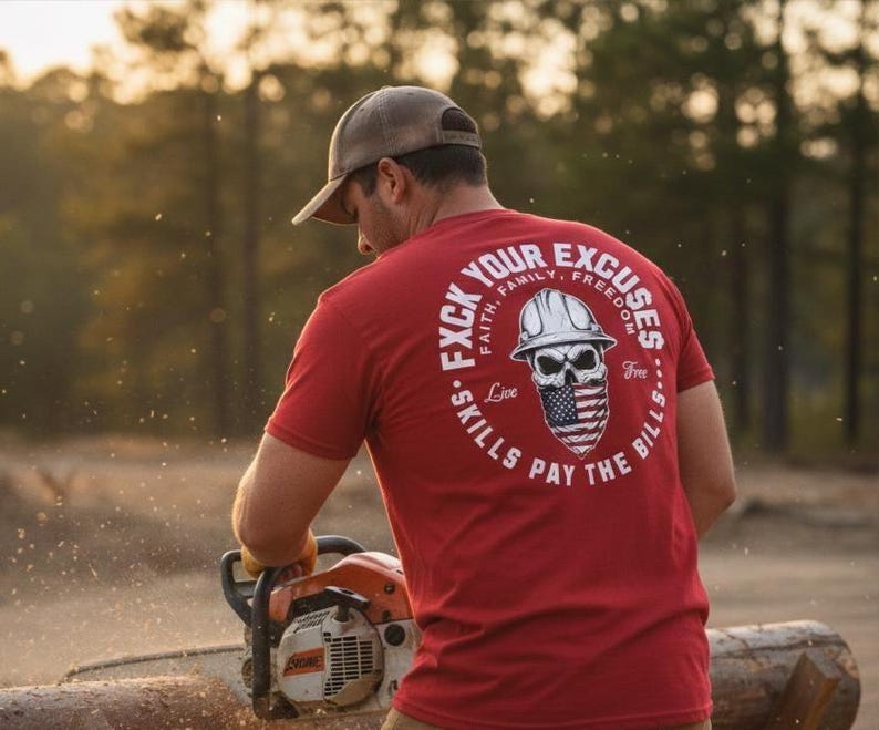 May include: A red t-shirt with a graphic on the back featuring a skull wearing a hard hat and an American flag bandana. The text reads "F*ck Your Excuses, Skills Pay The Bills". The person is using a chainsaw.