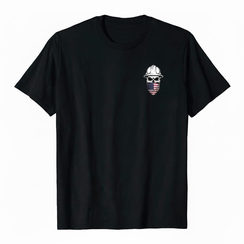 May include: Black t-shirt featuring a small graphic of a skull wearing a white hard hat and a face covering with an American flag design. The skull graphic is centered on the chest of the shirt.