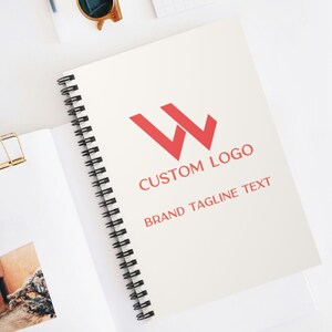 Peut inclure: Un carnet à spirales blanc avec un logo rouge de deux lettres "W" qui se chevauchent. Le texte "CUSTOM LOGO" et "BRAND TAGLINE TEXT" est imprimé sous le logo.