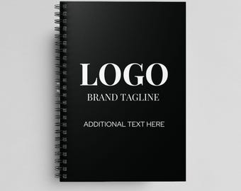 May include: Black spiral bound notebook with white text that reads "LOGO BRAND TAGLINE ADDITIONAL TEXT HERE".