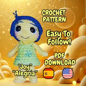 Puede incluir: Patrón de crochet para una muñeca amigurumi amarilla y verde con pelo azul. La muñeca se llama "Joy" y "Alegría". El patrón es fácil de seguir y viene como descarga PDF. La imagen incluye las banderas de España y los Estados Unidos.