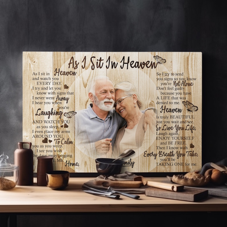 May include: A wooden sign with a photo of an older couple, a butterfly design, and the text "As I Sit In Heaven" and "So Live You Life".