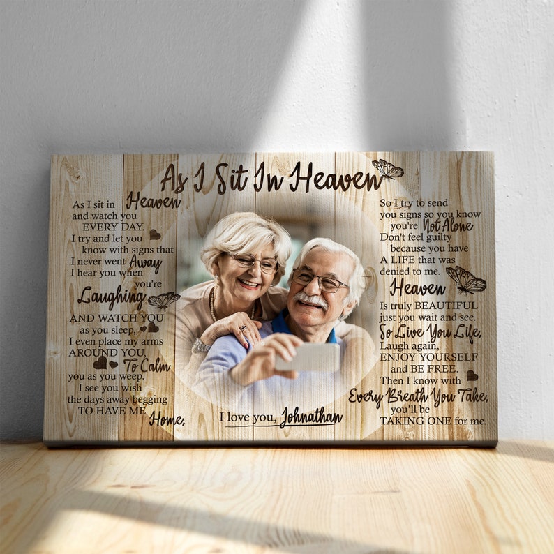 May include: A wooden sign with a photo of an older couple smiling and taking a selfie. The sign has a message about heaven and the text "As I Sit In Heaven" and "I love you, Johnathan".