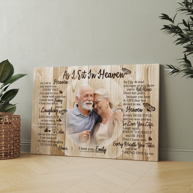 May include: A wooden canvas print with a photo of an older couple embracing. The print features a poem about Heaven and the love between two people. The poem reads "As I Sit In Heaven" and "I love you, Emily".