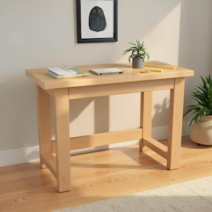 Può includere: Una scrivania in legno color chiaro con un piano rettangolare e quattro robuste gambe. La scrivania ha un design semplice ed è posizionata contro un muro di colore neutro. Una piccola pianta in vaso, libri e un quadro con cornice di un gufo sono sulla scrivania.