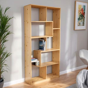 Puede incluir: Una estantería alta de madera clara con múltiples compartimentos de varios tamaños. Algunas estanterías contienen libros. La estantería está hecha de madera natural y se apoya contra una pared gris claro. El diseño es moderno y funcional.