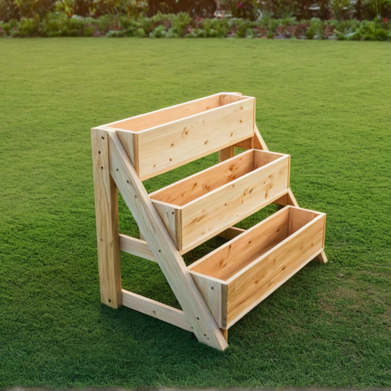 May include: A three-tiered wooden planter box, constructed from light-colored wood. The planter has three rectangular containers, each positioned at a different level. The structure is set on a green lawn.