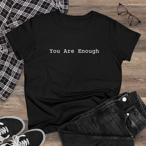 以下が含まれることがあります： 白い文字で「You Are Enough」と書かれた黒いTシャツです。