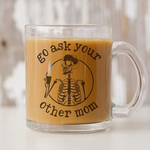 May include: A clear glass coffee mug with a black and white skeleton graphic and the text "go ask your other mom".