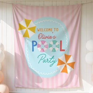 Może przedstawiać: Różowo-biały sztandar w paski z napisem "Welcome to Olivia's Pool Party" w kolorze niebieskim i zielonym. Na sztandarze znajdują się ilustracje żółto-białego parasola, pomarańczowo-białego parasola i dwóch kół ratunkowych. Po obu stronach znajdują się białe i brzoskwiniowe balony.