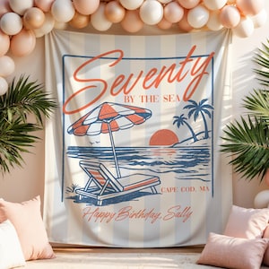 May include: A beach-themed banner with the words "Seventy by the Sea" and a beach scene illustration. The banner includes a beach umbrella, a lounge chair, and the text "Happy Birthday Sally". The banner is surrounded by balloons and palm leaves.