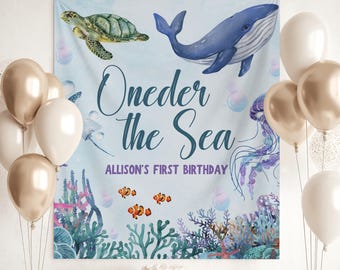 Peut inclure: Une scène de fête d'anniversaire avec une bannière indiquant "Oneder the Sea" et "Allison's First Birthday". La bannière présente des illustrations d'une tortue de mer, d'une baleine, d'une méduse et de poissons-clowns. Des ballons, des cadeaux et un gâteau complètent le décor festif.