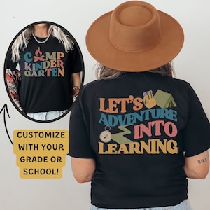 Puede incluir: Camiseta negra con el texto "Let's Adventure into Learning" en letras de colores. La camiseta también presenta una brújula, un sendero de senderismo, una mochila y una tienda de campaña. El texto "Camp Kindergarten" es visible en una camiseta negra que lleva una persona en el fondo.