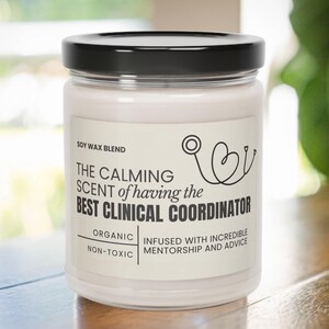 Może przedstawiać: Biała świeca sojowa z czarną pokrywką. Etykieta głosi "The calming scent of having the best clinical coordinator". Zawiera również napisy "Soy wax blend", "Organic", "Non-toxic" i "Infused with incredible mentorship and advice".