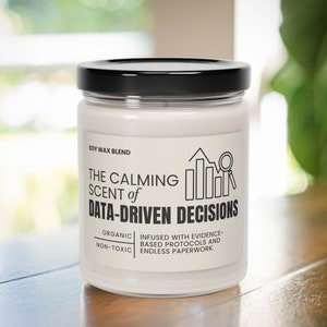 Könnte beinhalten: Ein weißes Kerzengefäß mit schwarzem Deckel und einem Etikett mit der Aufschrift "The Calming Scent of Data-Driven Decisions". Das Etikett trägt außerdem die Aufschrift "Soy Wax Blend", "Organic", "Non-Toxic", "Infused with evidence-based protocols and endless paperwork".