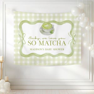 May include: A light green and white gingham backdrop with a watercolor design. The design features a cup of matcha with a heart design, and the text "Baby, we love you SO MATCHA" and "MADISON'S BABY SHOWER".