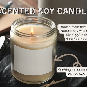 Puede incluir: Una vela de vidrio transparente en un frasco con una etiqueta blanca y una tapa negra. La vela est&aacute; encendida y la llama es visible. La vela est&aacute; hecha de cera de soja natural y tiene un tiempo de combusti&oacute;n de 40 horas. La vela mide 2,8 pulgadas por 3,5 pulgadas y pesa 9 onzas. El texto "Choose from five scents" es visible en la imagen. El texto "Looking to customize? Reach out!" tambi&eacute;n es visible en la imagen.