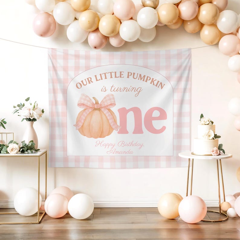 Op de afbeelding: Een roze en witte geruite achtergrond met de tekst "Our Little Pumpkin is turning one" en "Happy Birthday Amanda". Een aquarel pompoen met een strik is afgebeeld. Ballonnen in roze, witte en perziktinten zijn rond de achtergrond geplaatst.