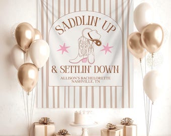 May include: A party scene with a banner reading "Saddlin' Up & Settlin' Down" with a cowboy boot and hat illustration. Balloons in gold and white, gifts, and a cake are arranged on a table, creating a festive atmosphere for a bachelorette party.