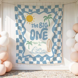 Könnte beinhalten: Ein blau-weiß kariertes Banner mit dem Text "The Big One" und tropischen Illustrationen, darunter eine Sonne, Palmen, ein Surfbrett und Wellen. Das Banner hat einen blauen, wellenförmigen Rand. Auf beiden Seiten befinden sich weiße und pfirsichfarbene Ballons.