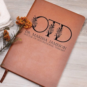 May include: Brown leather journal with the letters "OT" in a circle with leaves around them. The text "Dr. Marissa Jameson, Doctor of Occupational Therapy" is below the letters.