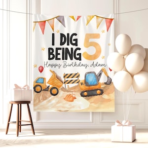 May include: A white banner with the text "I DIG BEING 5 Happy Birthday, Adam" and construction-themed illustrations. The banner features a dump truck, excavator, and construction signs. A cluster of white balloons and a gift box are also present.
