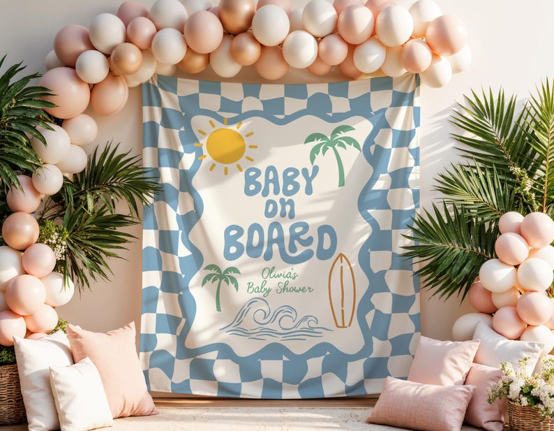 May include: A baby shower backdrop with a blue and white checkered pattern, featuring the text "Baby on Board" with a sun, palm trees, a surfboard, and waves. The scene is decorated with balloons and pillows.