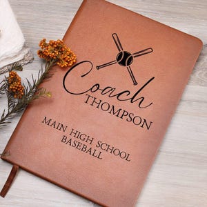 Peut inclure: Journal en cuir marron avec un motif de baseball et de batte, personnalisé avec le texte "Coach Thompson Main High School Baseball".