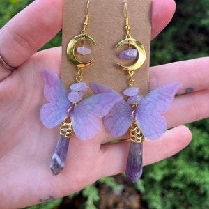 May include: Purple butterfly earrings with gold crescent moon charms and amethyst crystal drops.