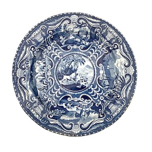 Puede incluir: Un plato decorativo redondo, azul y blanco, con un diseño detallado y ornamentado. El plato presenta una escena central rodeada de intrincados patrones e imágenes de animales y paisajes. El diámetro del plato es de aproximadamente 25 cm.