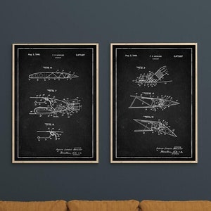 May include: Two black and white vintage patent drawings of an aircraft design. The drawings are framed and hung on a dark blue wall above a brown couch.