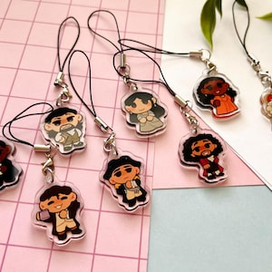 K&ouml;nnte beinhalten: Acht bunte Comicfiguren-Anh&auml;nger an schwarzen Schnur-Handy-Anh&auml;ngern. Die Figuren stammen aus dem Musical Hamilton.