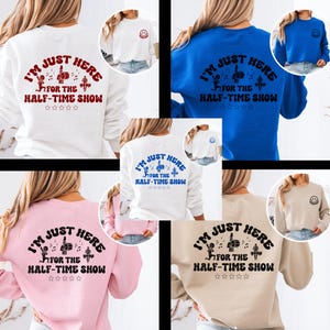 Può includere: Diverse felpe bianche, blu, rosa e beige, ognuna con la scritta "I'M JUST HERE FOR THE HALF-TIME SHOW". Il design include note musicali, un gesto della mano e stelle.