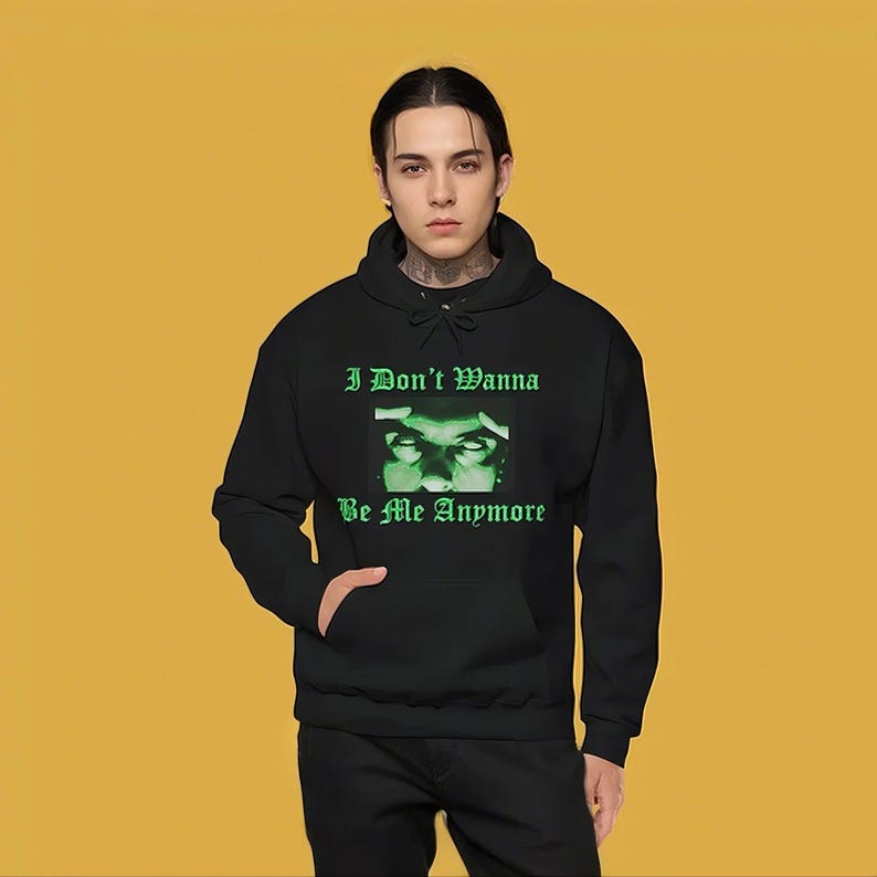 K&ouml;nnte beinhalten: Ein schwarzer Kapuzenpullover mit einem gr&uuml;nen Grafikdruck von Augen einer Person und dem Text "I Don't Wanna Be Me Anymore".