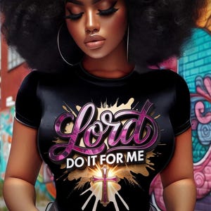 May include: Black t-shirt with the words "Lord DO IT FOR ME" in a pink and purple design. The shirt features a cross graphic with a gold and white background. The image shows a person with dark skin and large hoop earrings.