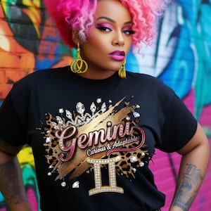 May include: Black t-shirt featuring a Gemini zodiac design. The design includes the word "Gemini" in a script font, the Gemini symbol, and the phrase "Curious & Adaptable". The design incorporates gold, brown, and diamond accents.
