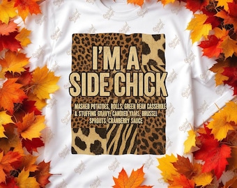 May include: White t-shirt with the text "I'M A SIDE CHICK" in a bold font, set against a leopard, zebra, and cheetah print design. The shirt lists side dishes. The image is framed by autumnal leaves in shades of red and orange.